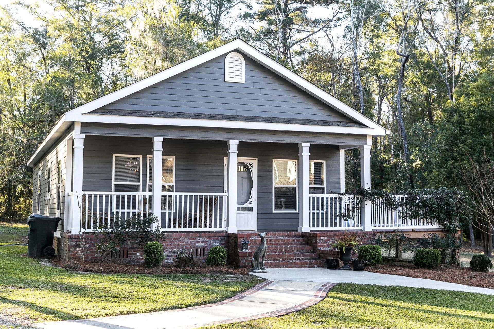 A small house with a porch railing and a walkway in front of it.