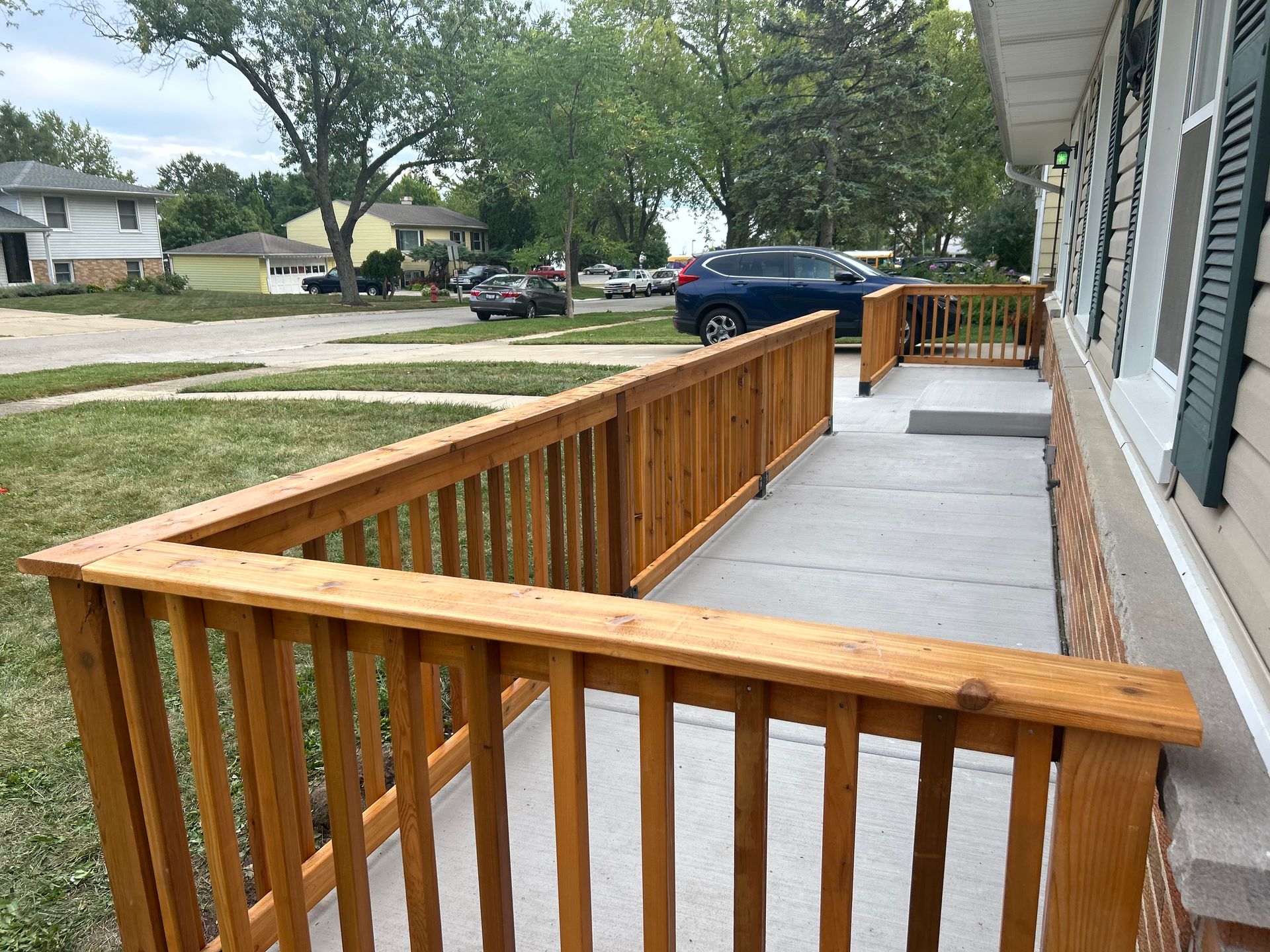A wooden deck with a ramp leading to the front of a house.