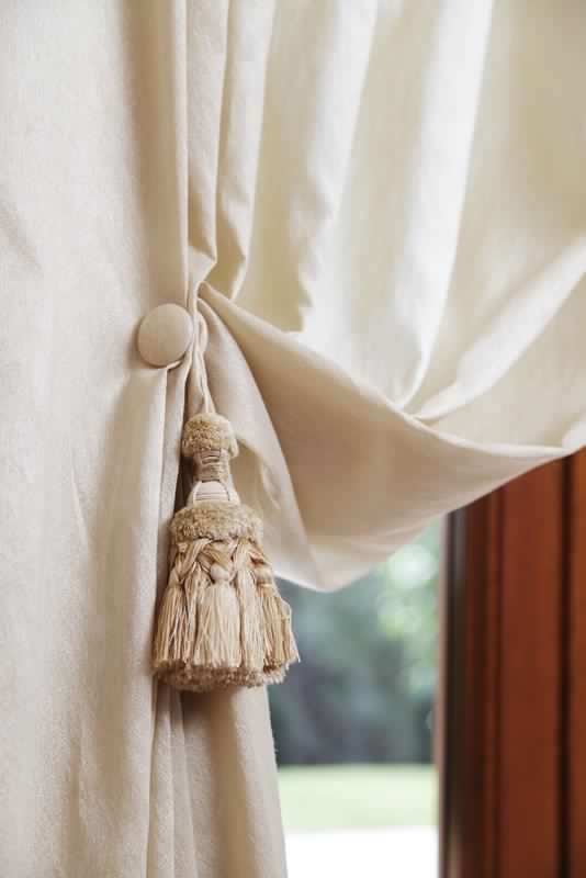 Un primo piano di una tenda bianca con una nappa attaccata.