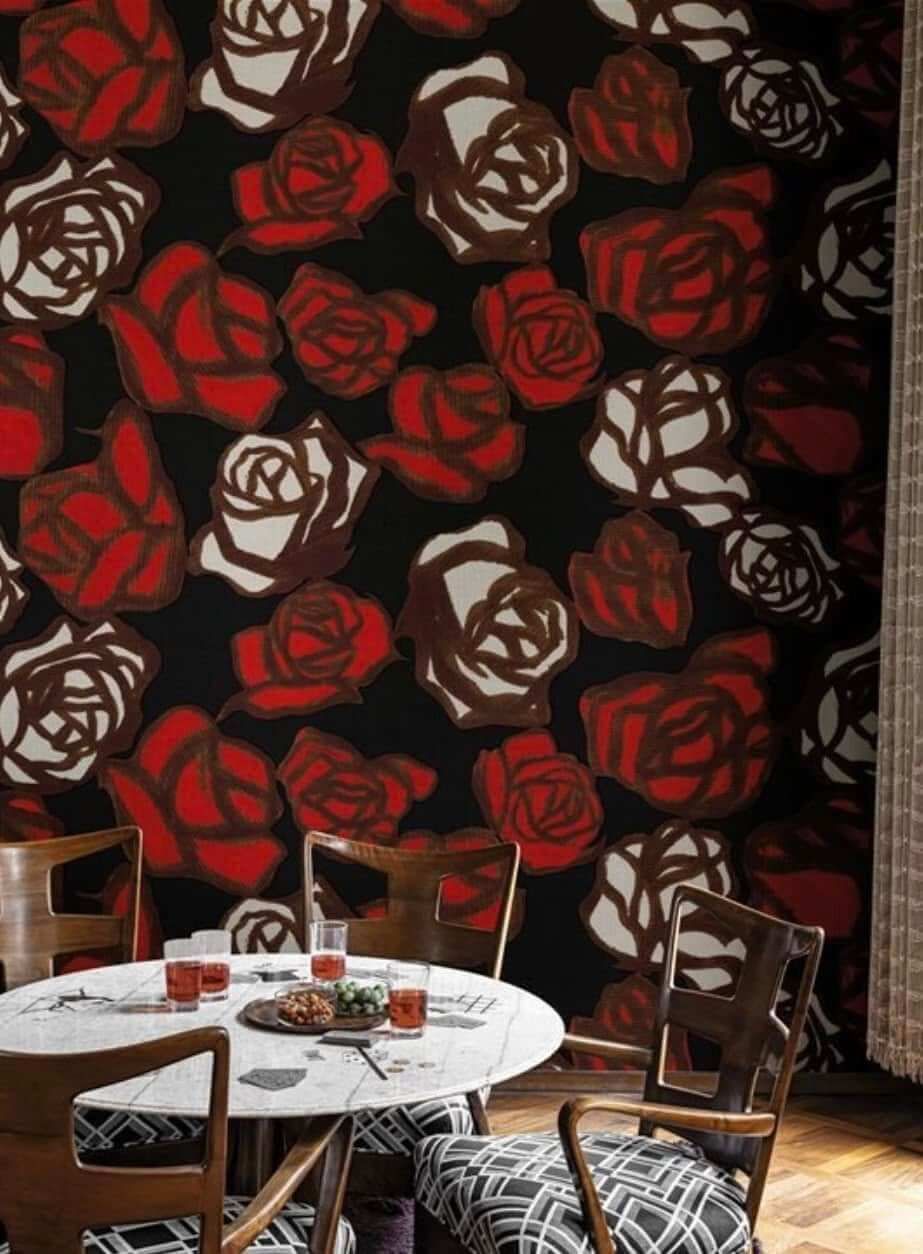 Una sala da pranzo con un tavolo e delle sedie e una parete con delle rose rosse