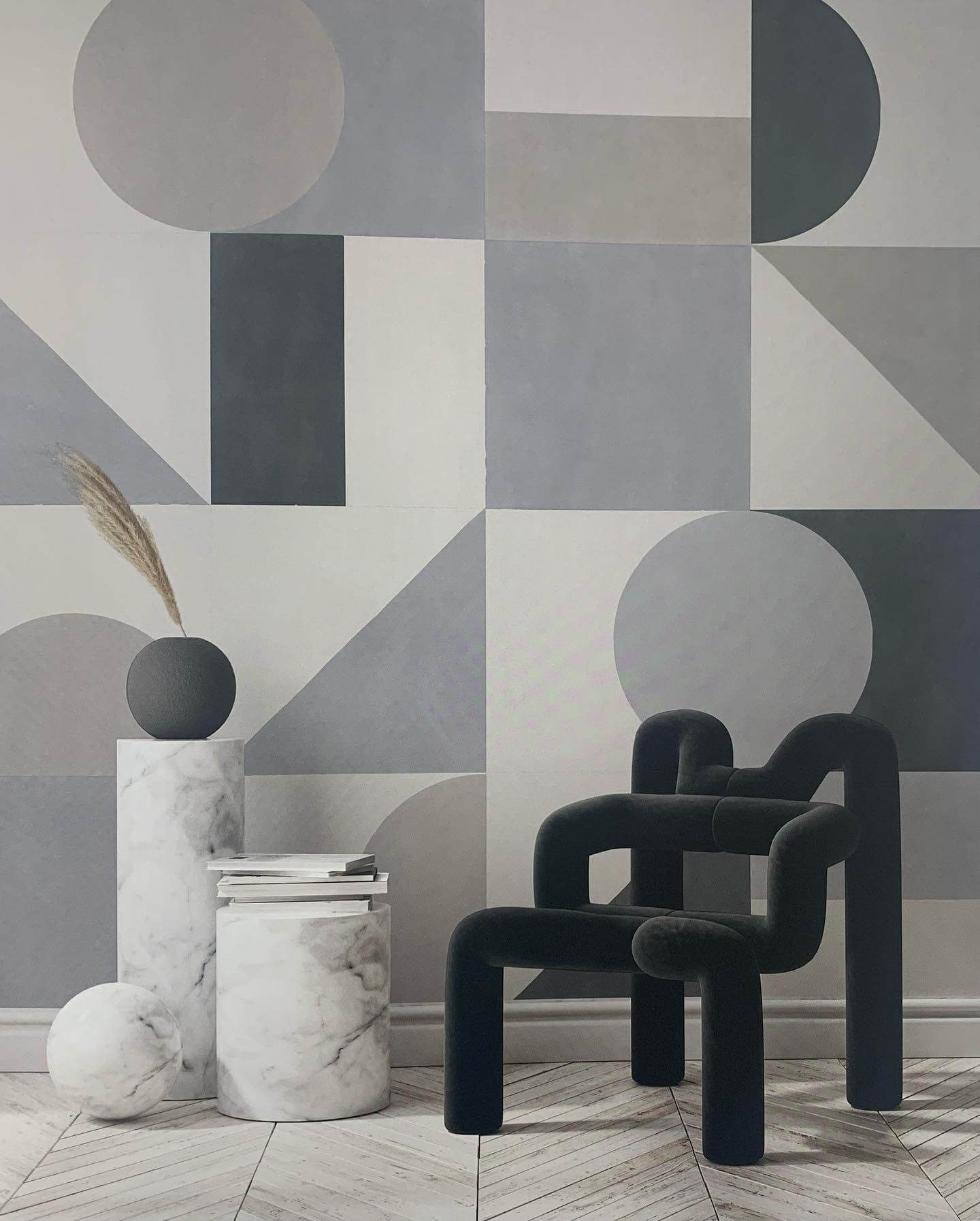 Una sedia è posta di fronte a una parete decorata con forme geometriche.