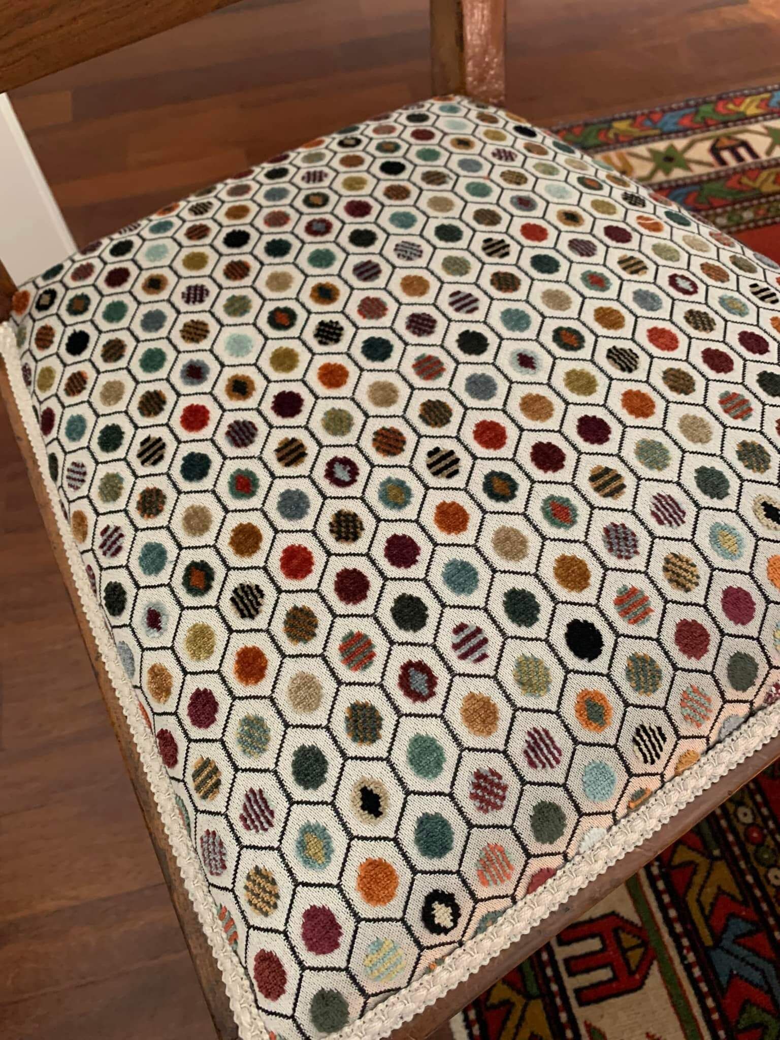 Una sedia con un tappeto colorato è appoggiata su un pavimento di legno.