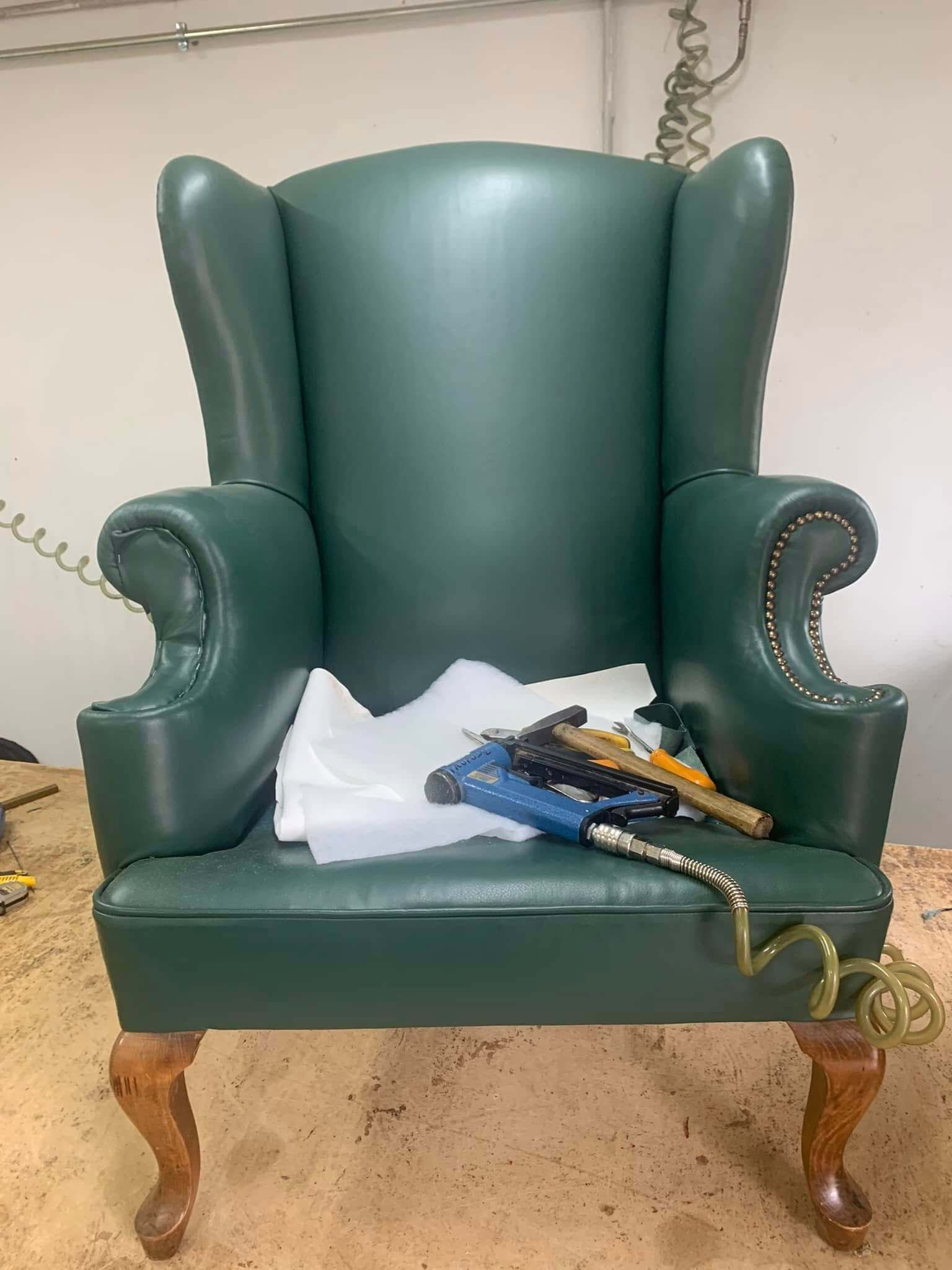 Una sedia in pelle verde è appoggiata su un tavolo di legno.