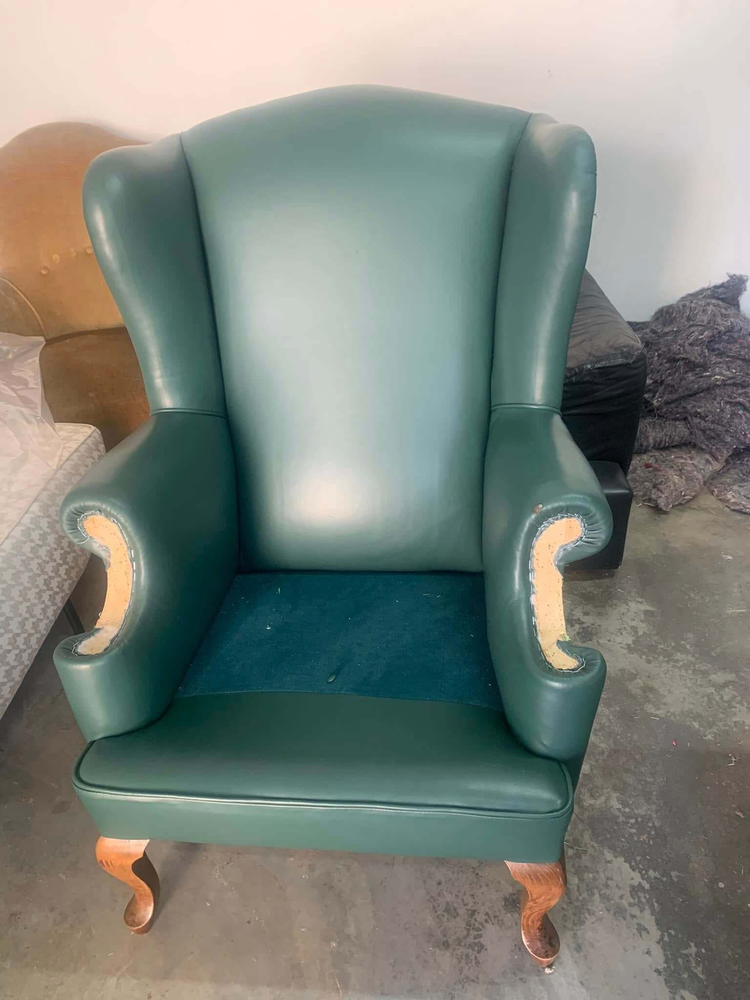 Una sedia di pelle verde è appoggiata sul pavimento in una stanza.