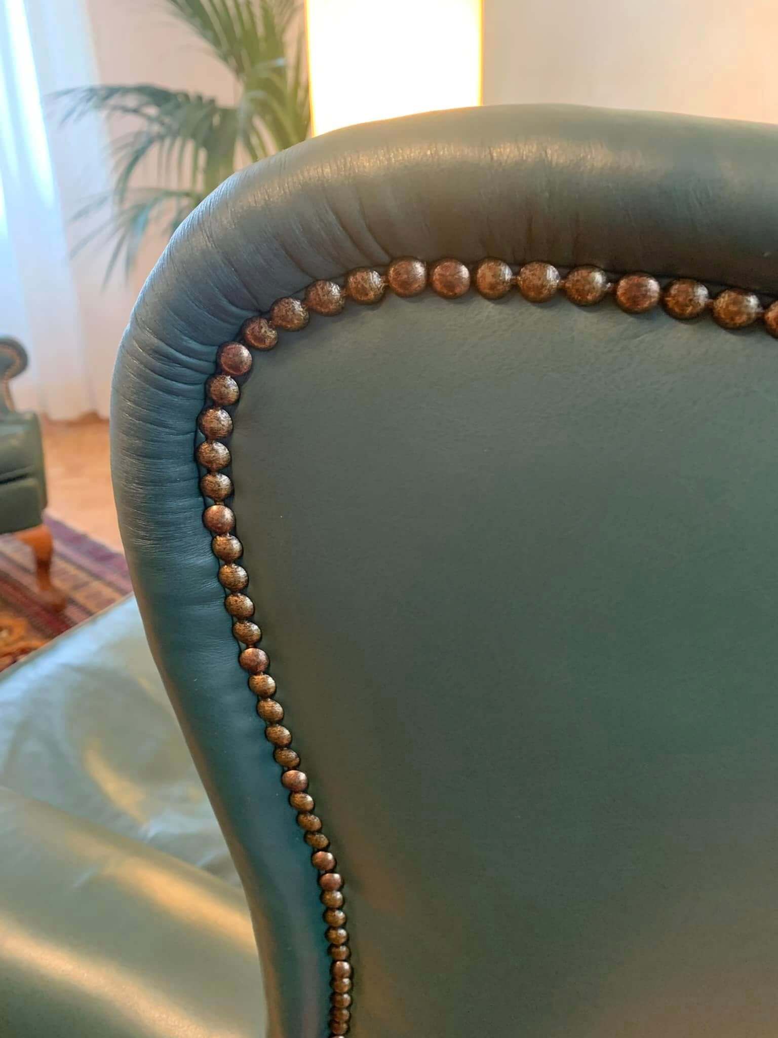 Lo schienale di una sedia in pelle verde con delle borchie.