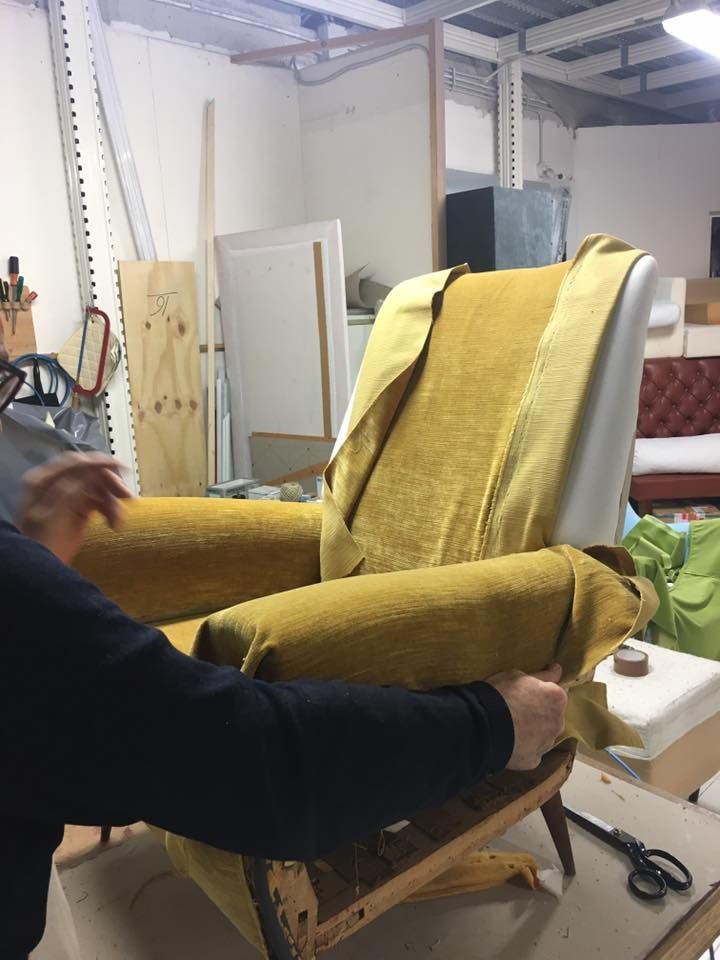 Una persona sta lavorando su una sedia gialla in una stanza.