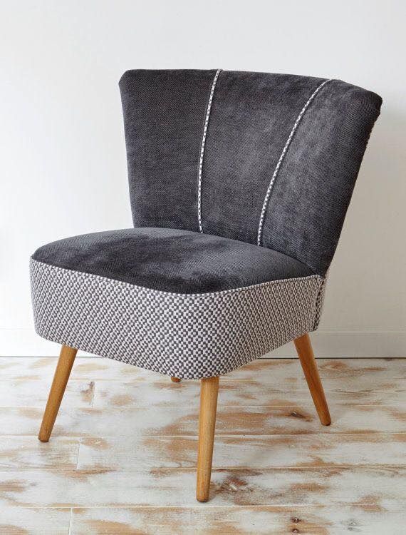 Una sedia grigia con le gambe di legno è appoggiata su un pavimento di legno.