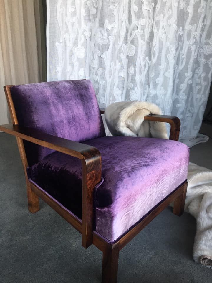 Una sedia viola è posta davanti a una tenda bianca.