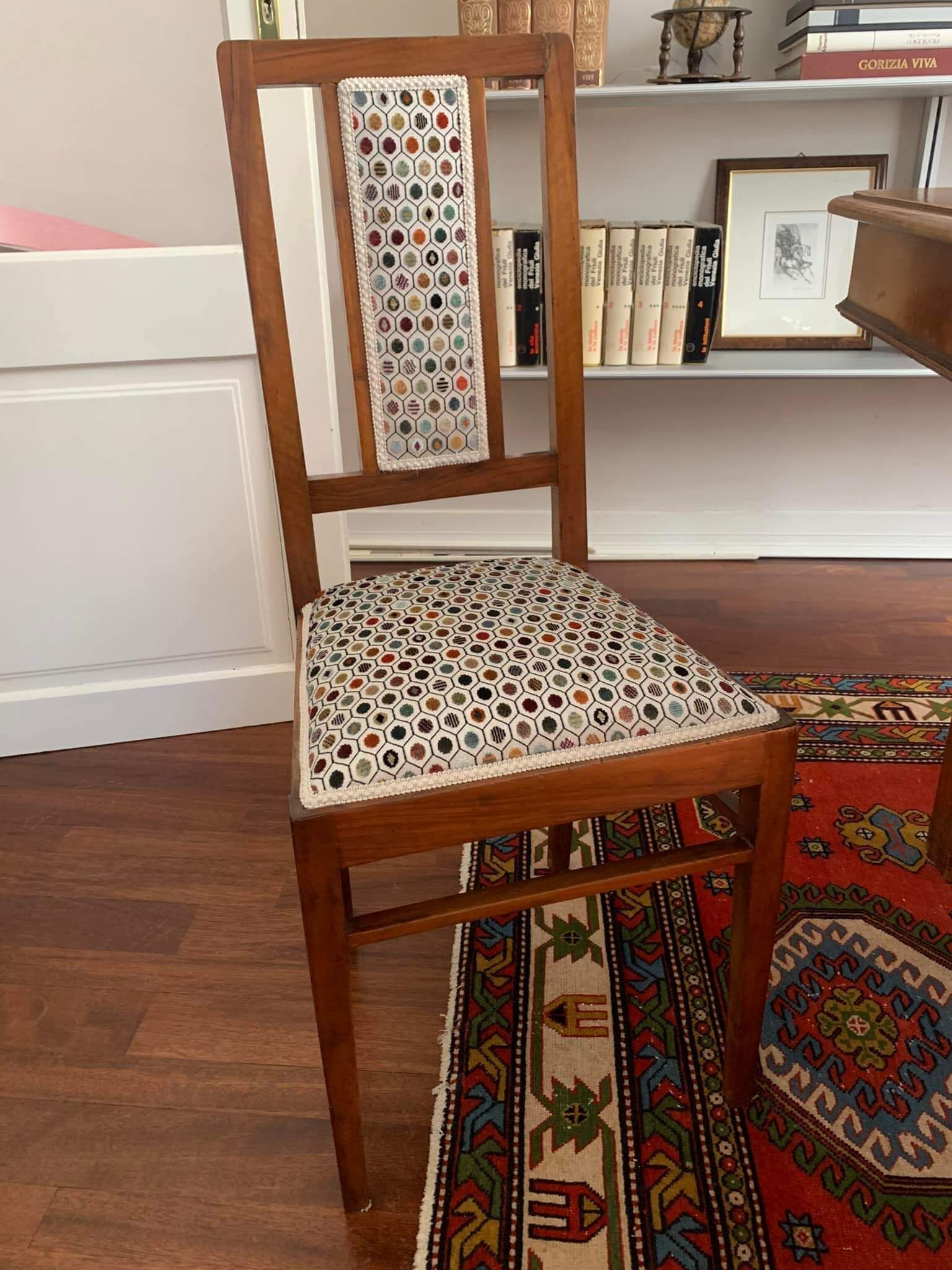 Una sedia di legno è appoggiata su un tappeto in un soggiorno.
