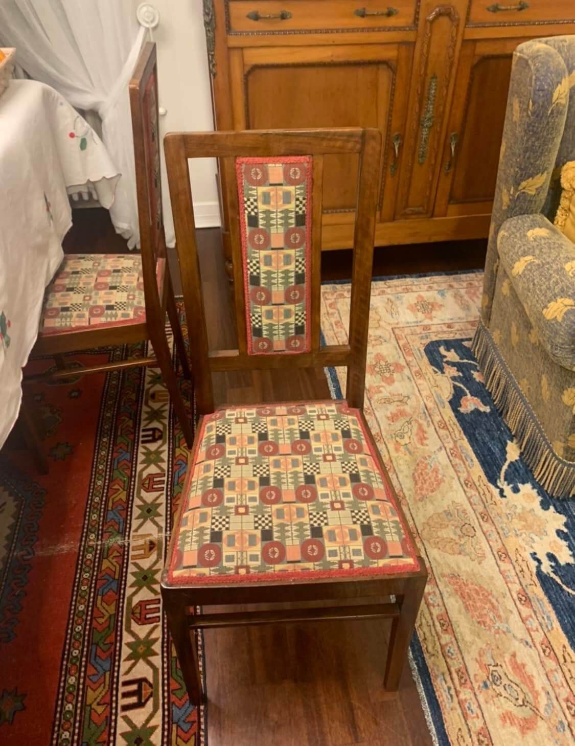 Una sedia di legno con un cuscino di seduta decorato è appoggiata su un tappeto in un soggiorno.