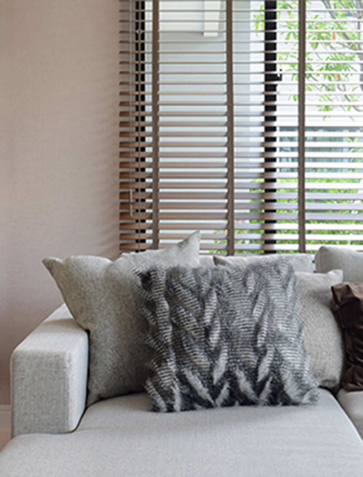 Un divano con un cuscino lavorato a maglia davanti a una finestra con le persiane.