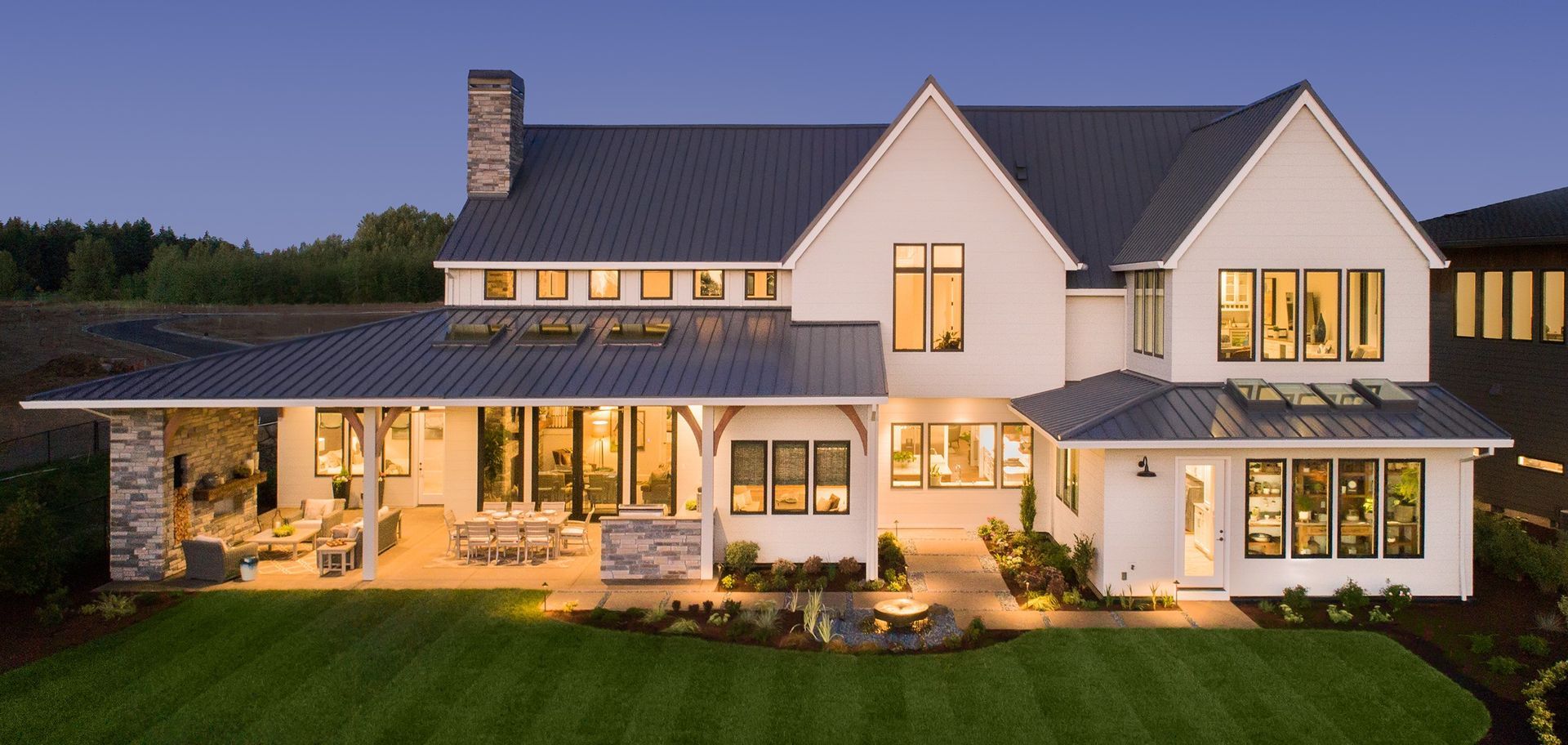 A large white house with a black roof is lit up at night