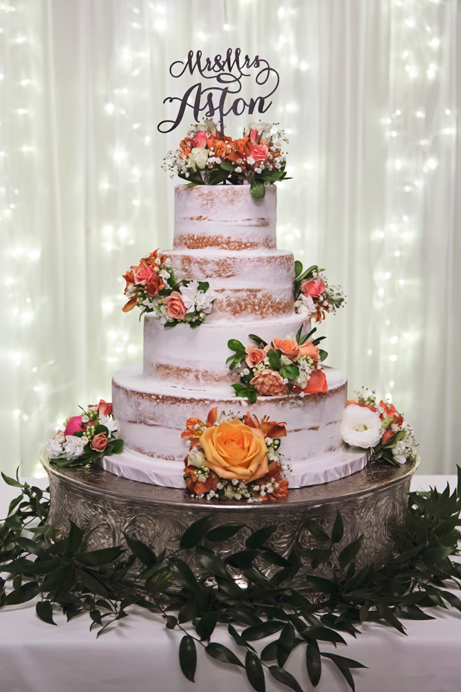 A wedding cake is sitting on top of a table with flowers.