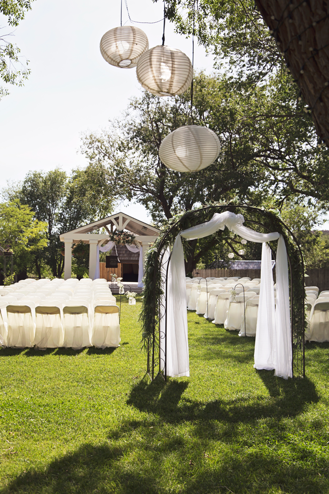 A wedding ceremony is taking place in the grass in front of a building.