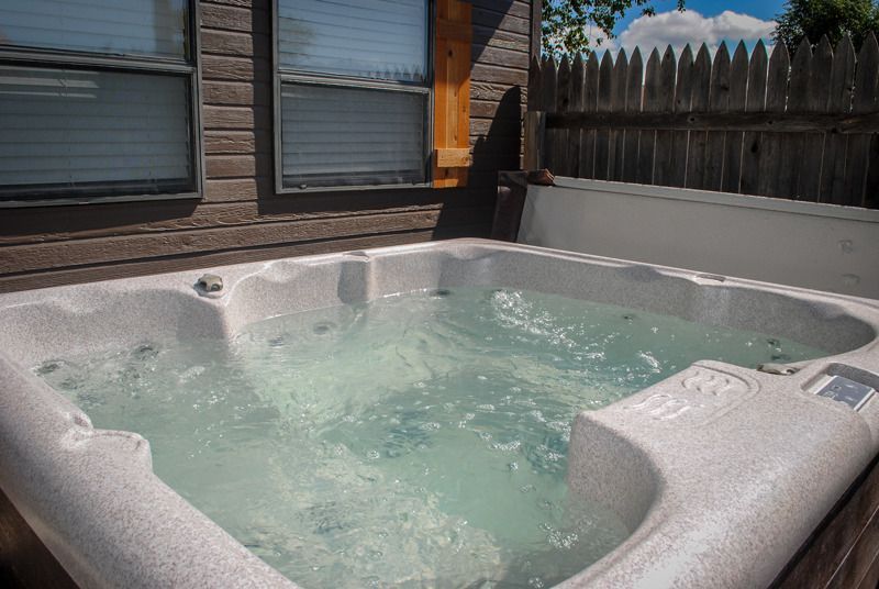 A hot tub is sitting on a deck outside of a house.