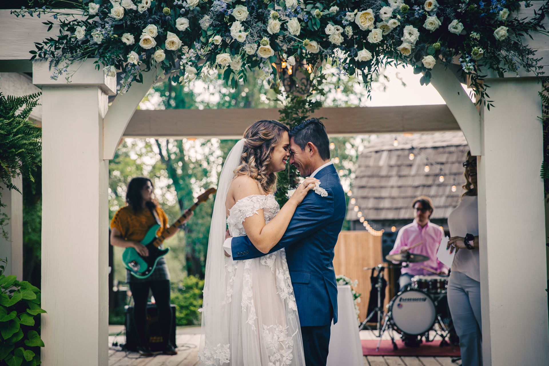 A bride and groom are dancing in front of a band at their wedding.