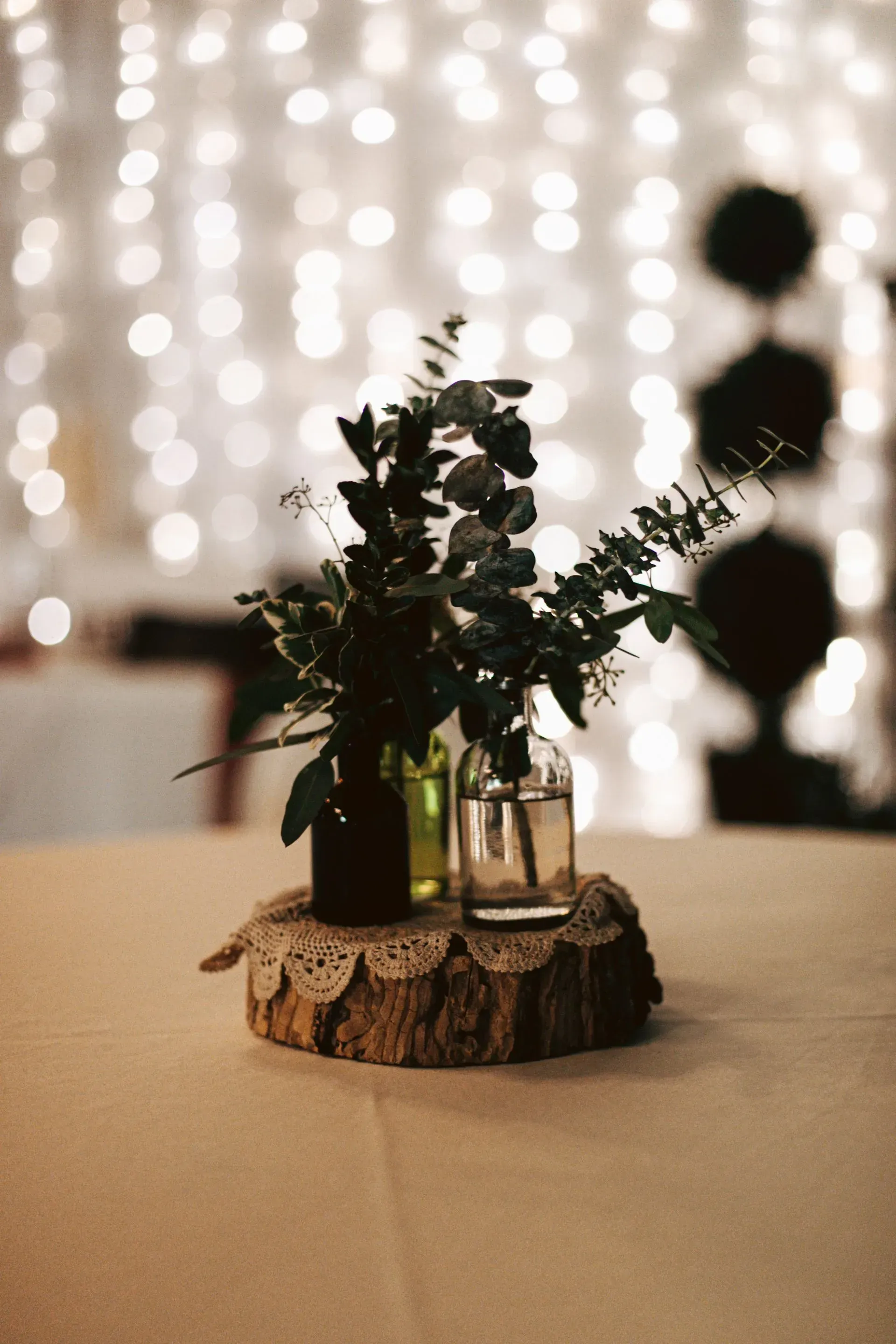 Two vases filled with flowers are sitting on a wooden stump on a table.
