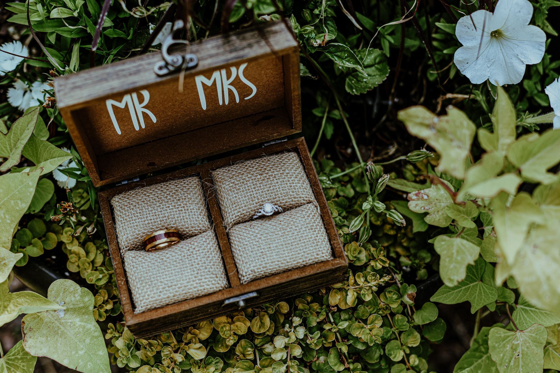 A wooden box filled with wedding rings and flowers.