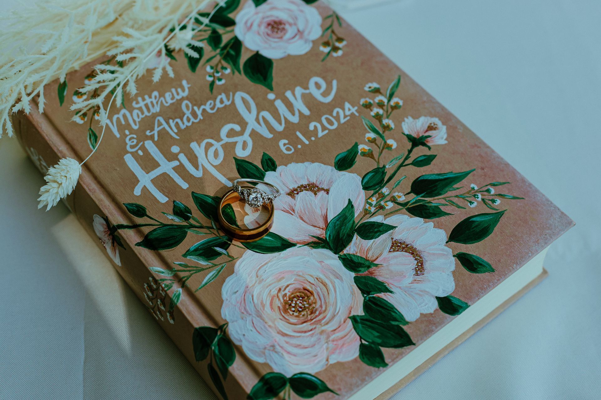 A book with a floral cover and wedding rings on it.
