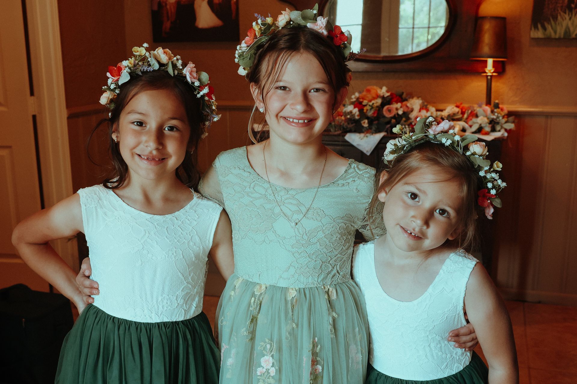Three little girls wearing flower crowns are posing for a picture.