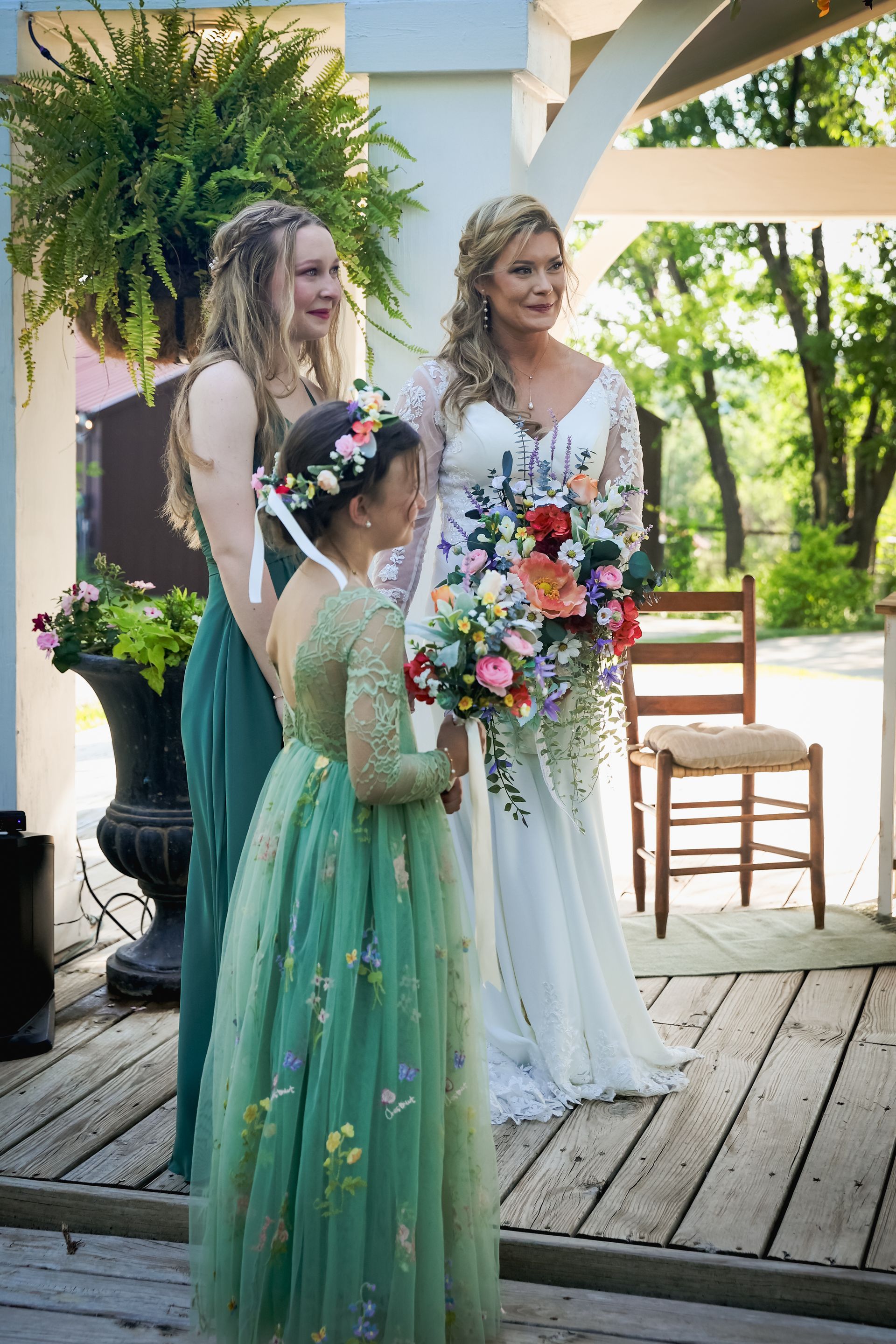 A bride and her bridesmaids are standing next to each other on a wooden deck.