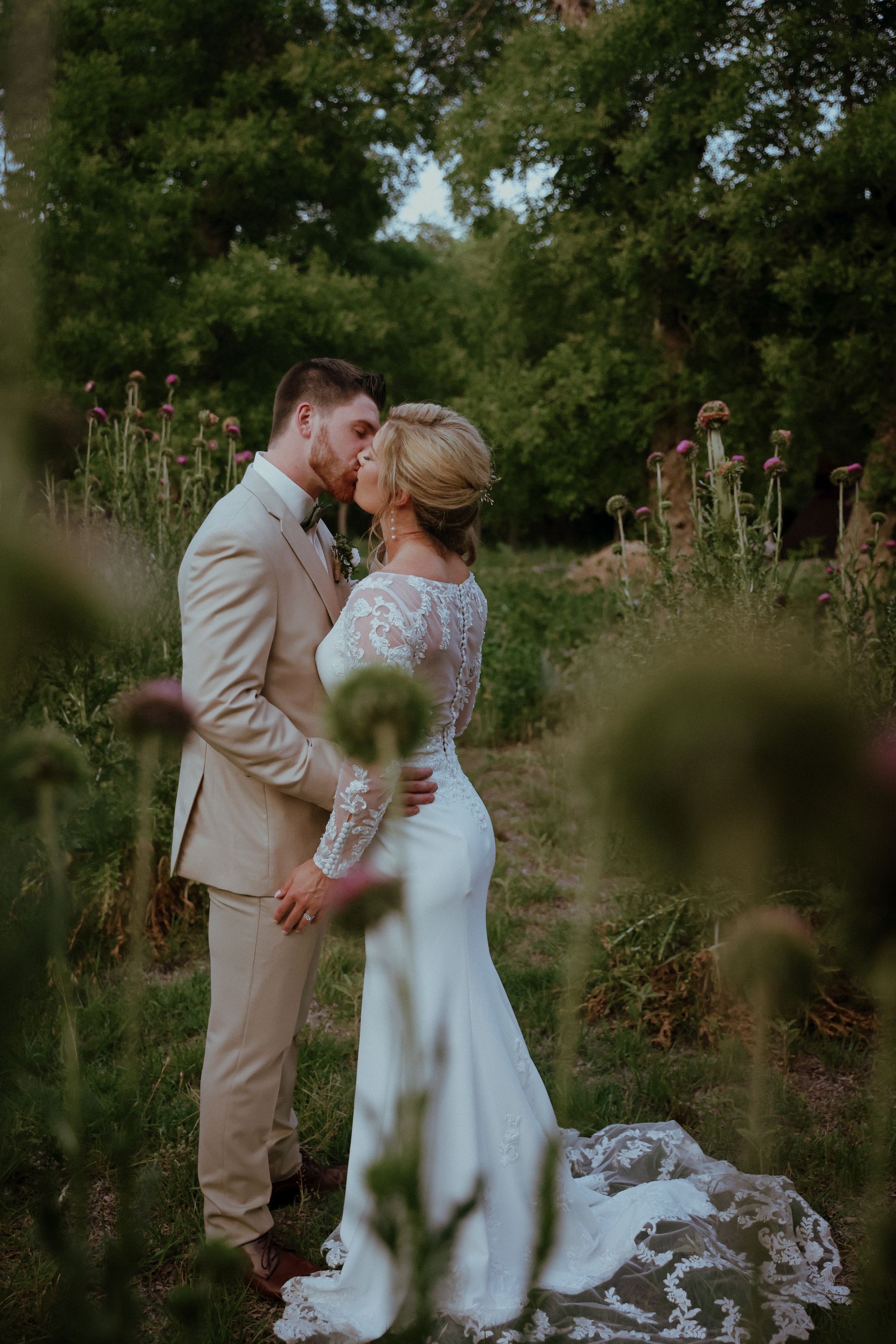 A bride and groom are kissing in a field.