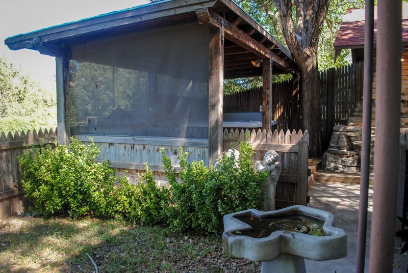 There is a bird bath in front of a screened in porch.