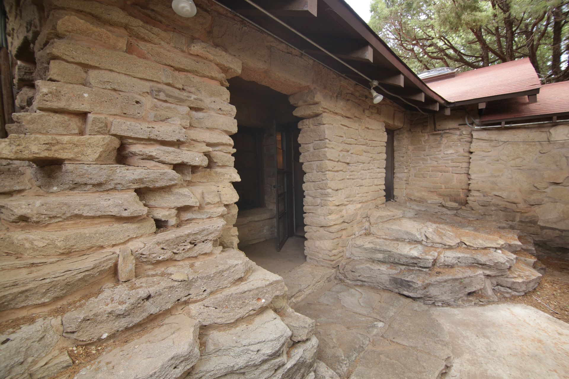 A brick building with a red roof and a stone wall
