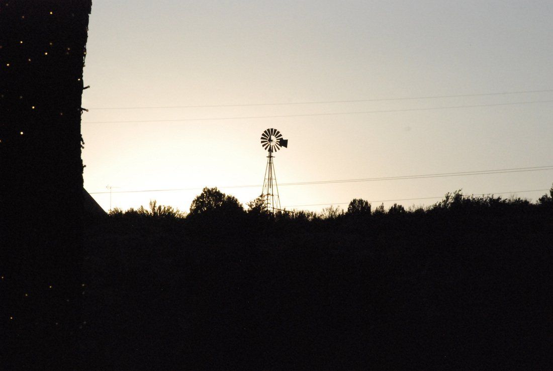 A windmill is silhouetted against a sunset sky