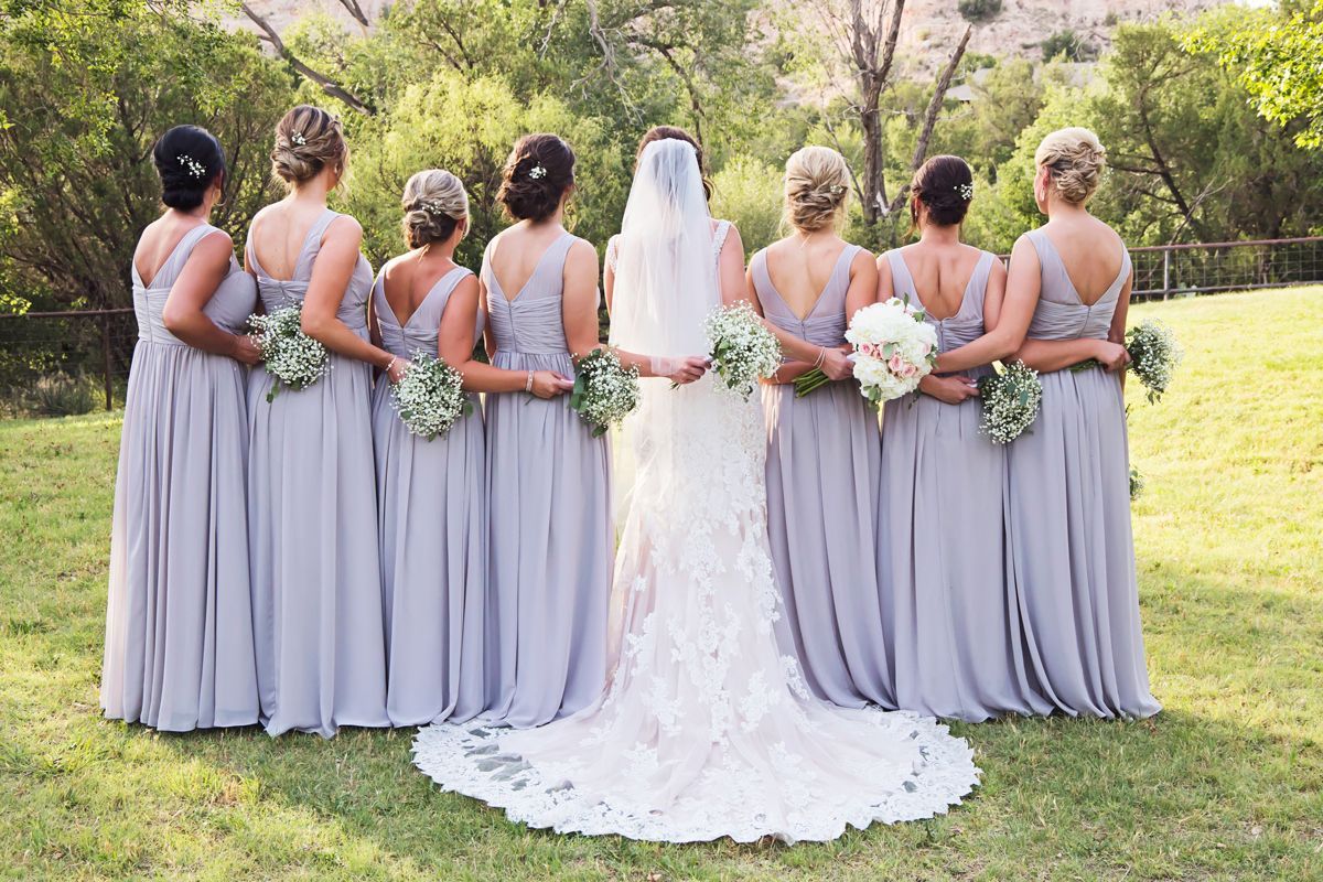 A bride and her bridesmaids are posing for a picture in a field.