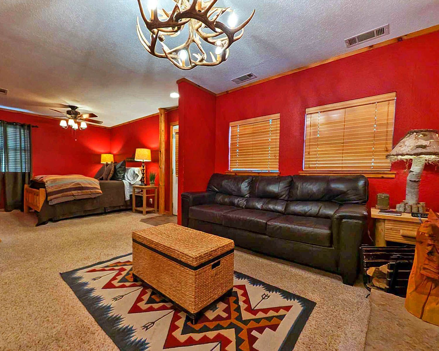 A living room with a couch , ottoman , rug and a bed.