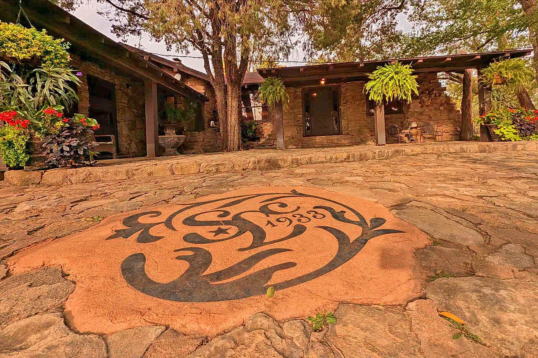 There is a logo on the ground in front of a stone building.