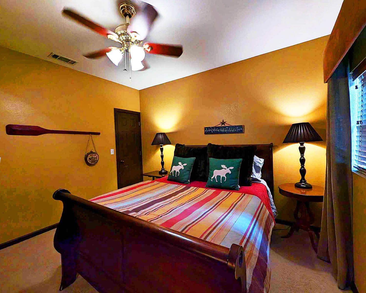 A bedroom with a sleigh bed and a ceiling fan