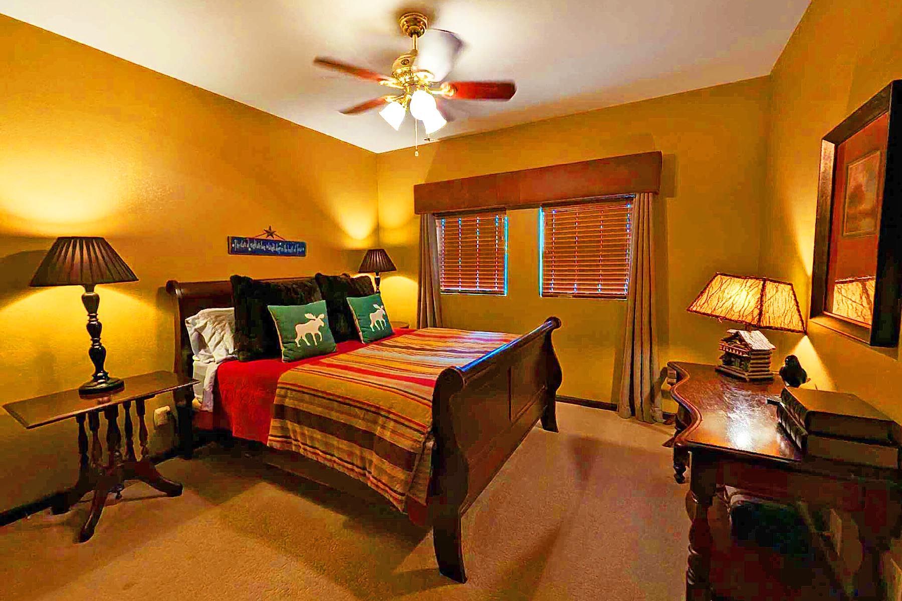 A bedroom with a king size bed and a ceiling fan.