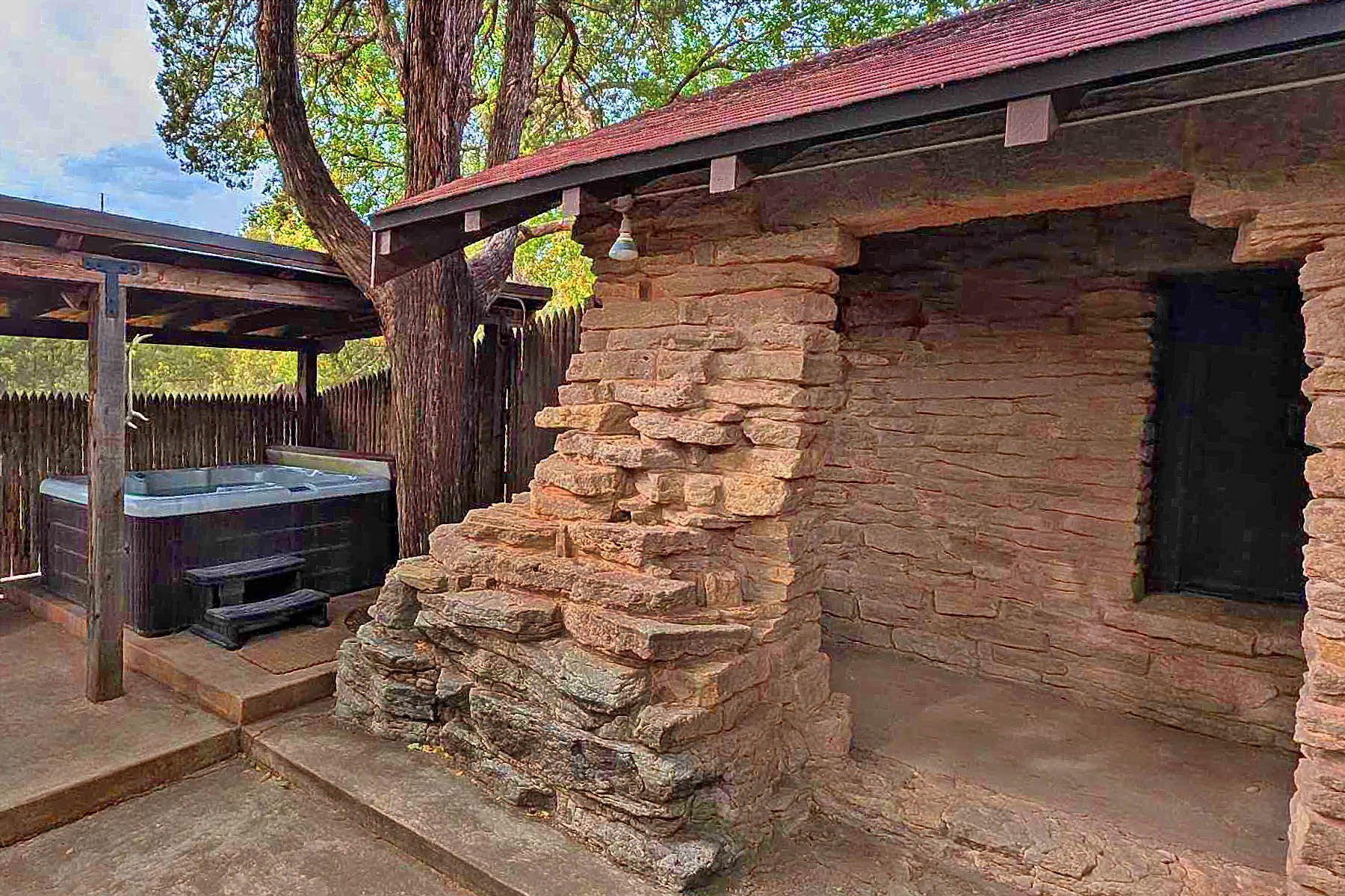 A stone building with a hot tub in the backyard.