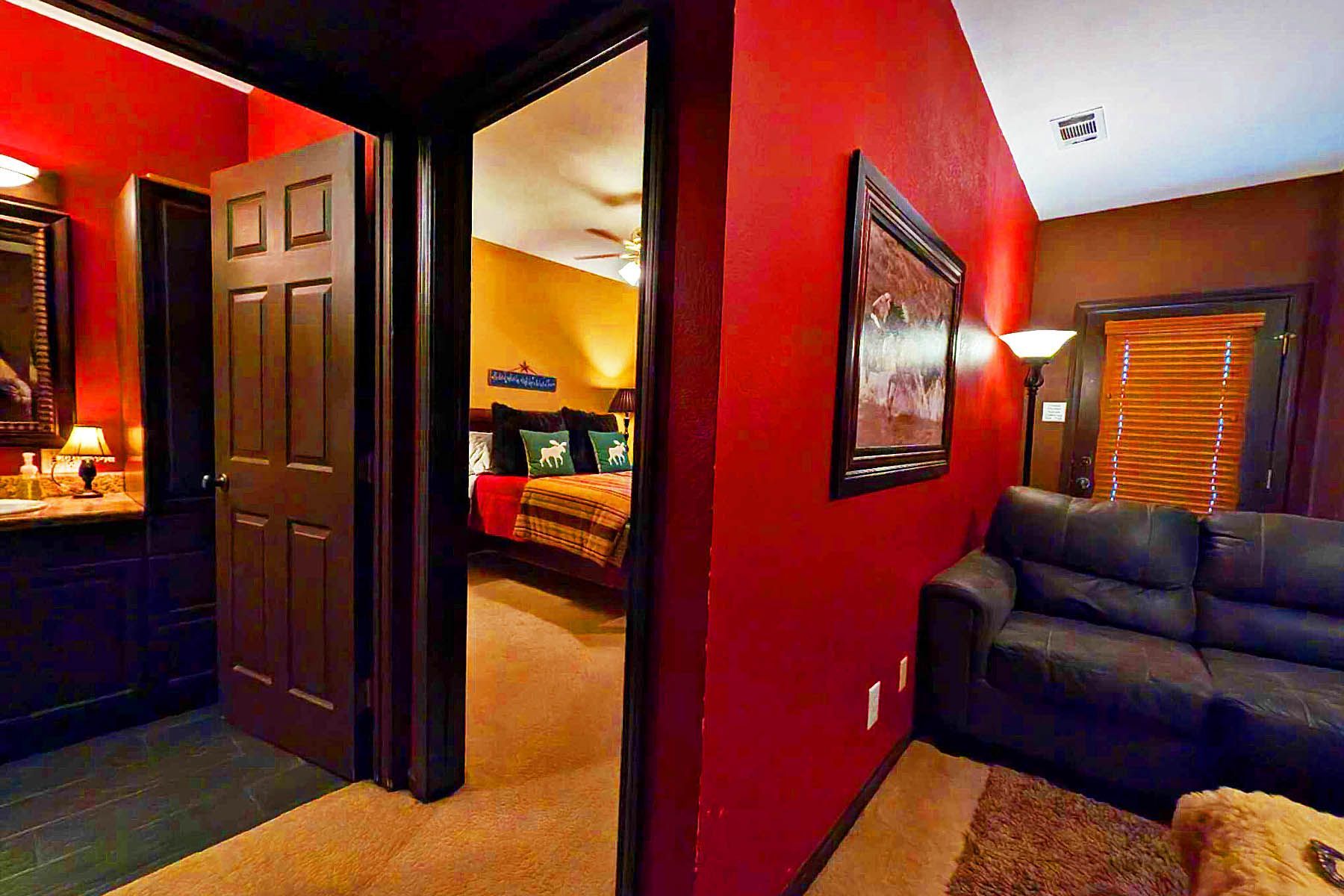 A bedroom with red walls and a black couch.