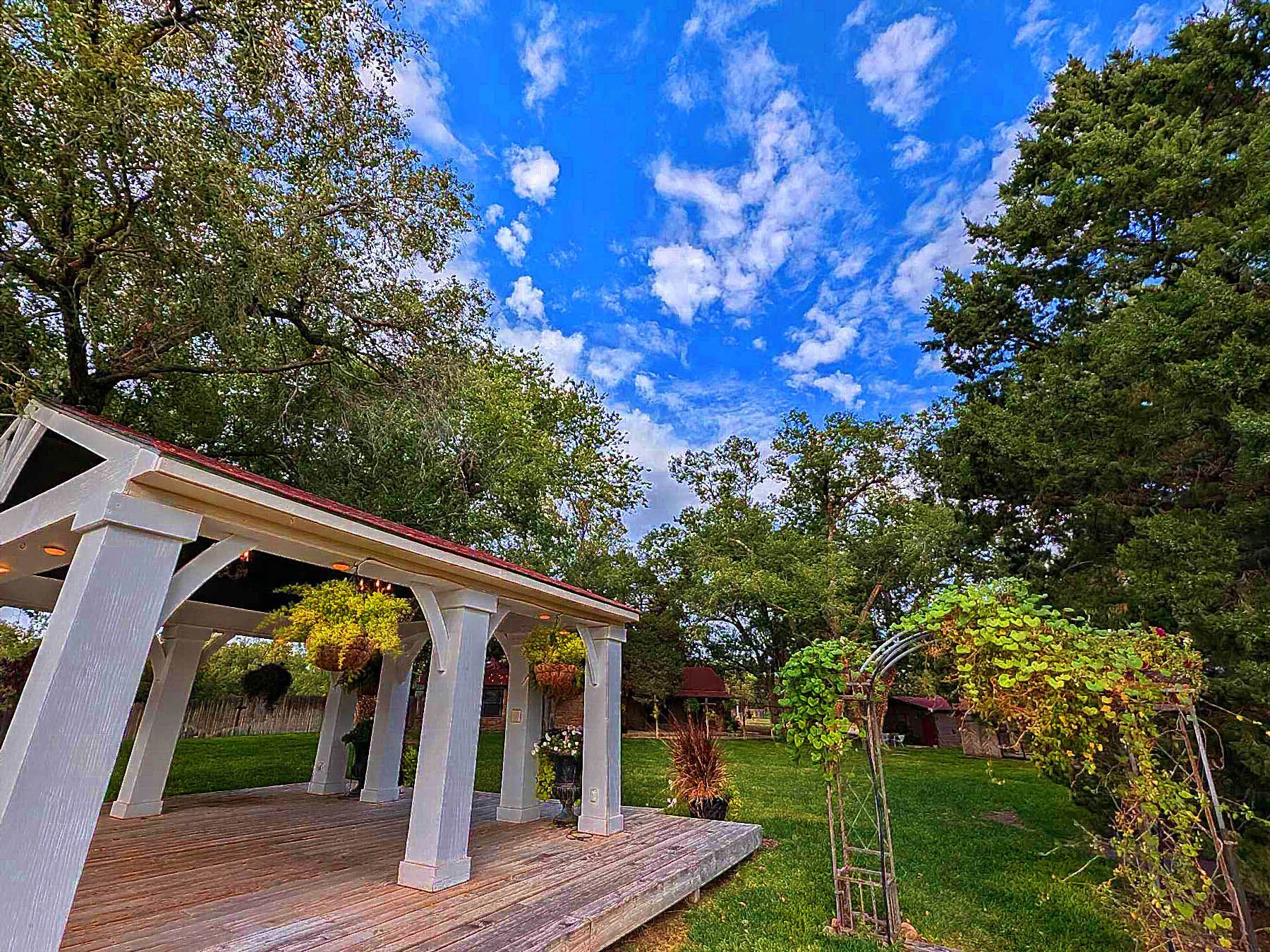 A gazebo in the middle of a park with trees and a blue sky in the background.