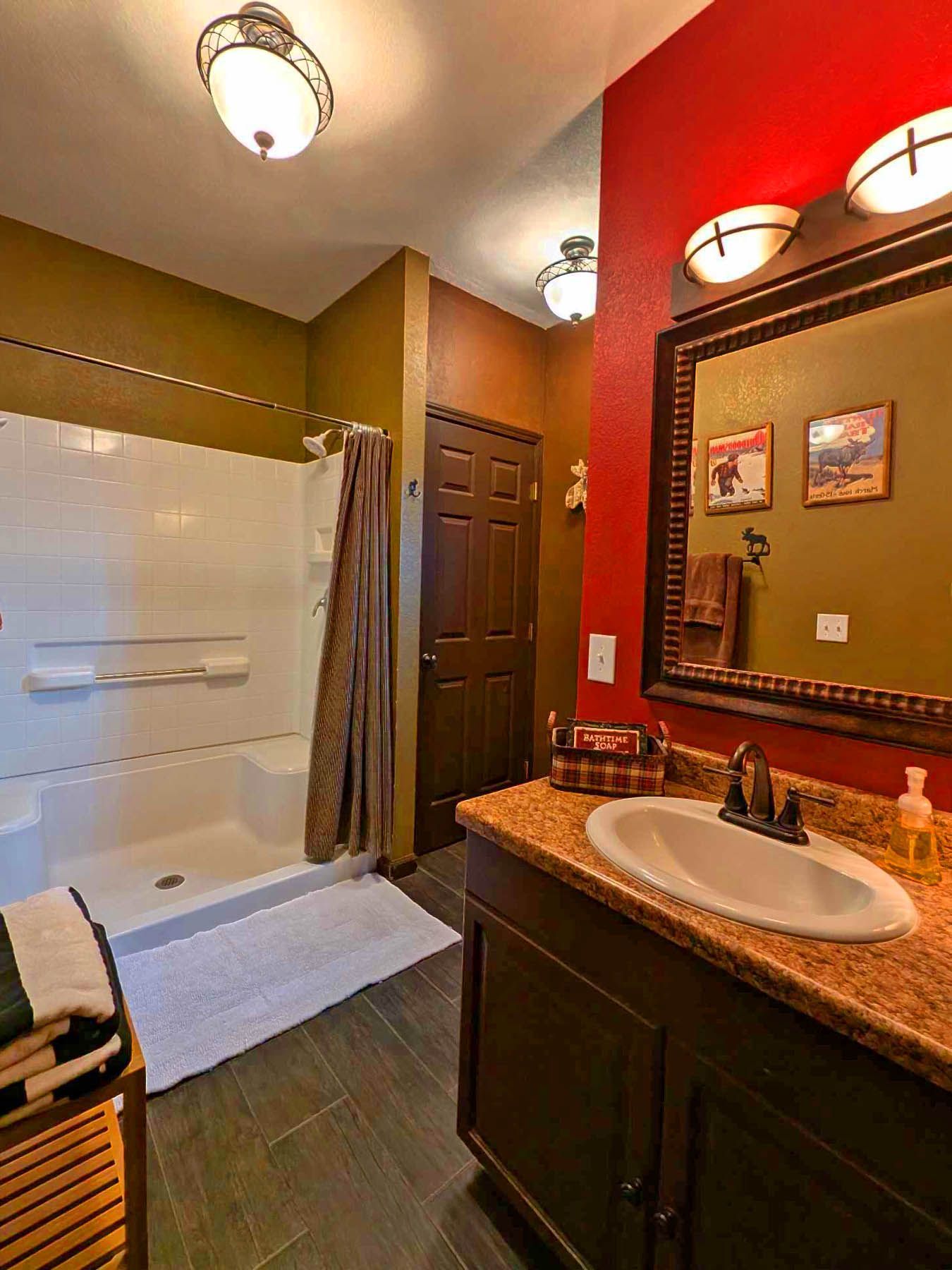 A bathroom with a sink , mirror and shower.
