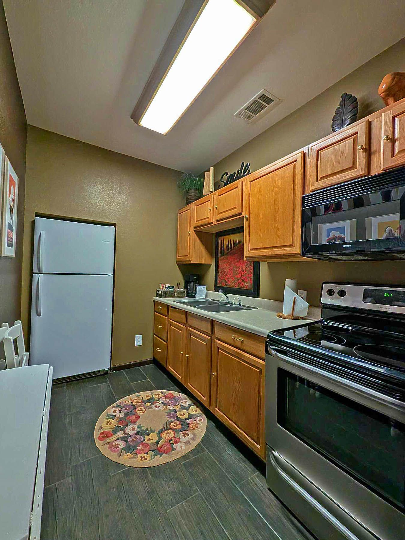 A kitchen with wooden cabinets , stainless steel appliances , a refrigerator , stove and microwave.