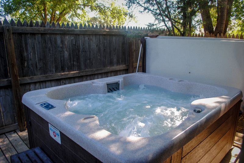 A hot tub is sitting on a wooden deck next to a wooden fence.