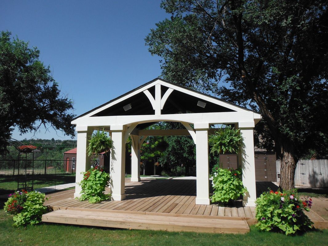 A white gazebo with a black roof is surrounded by trees