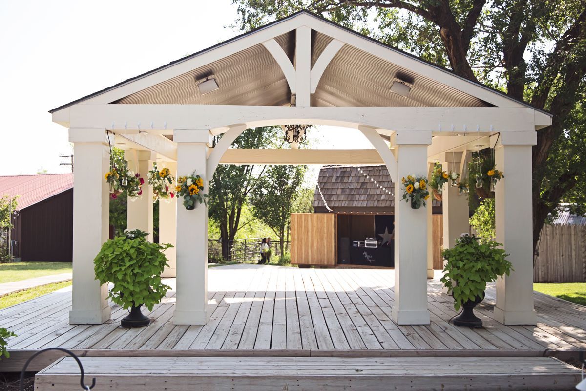 A white gazebo with flowers hanging from the columns