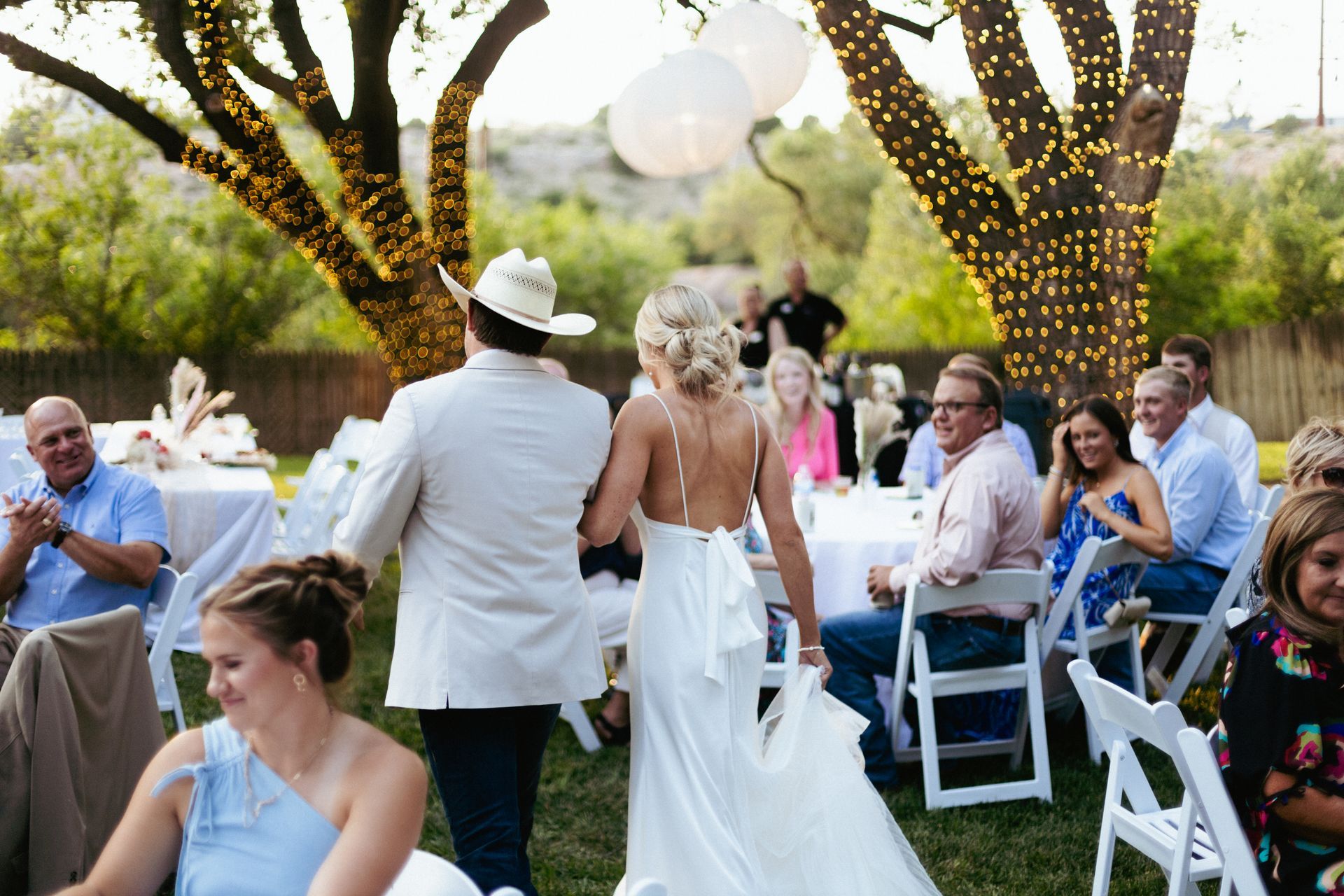 A bride and groom are walking down the aisle at their wedding reception.