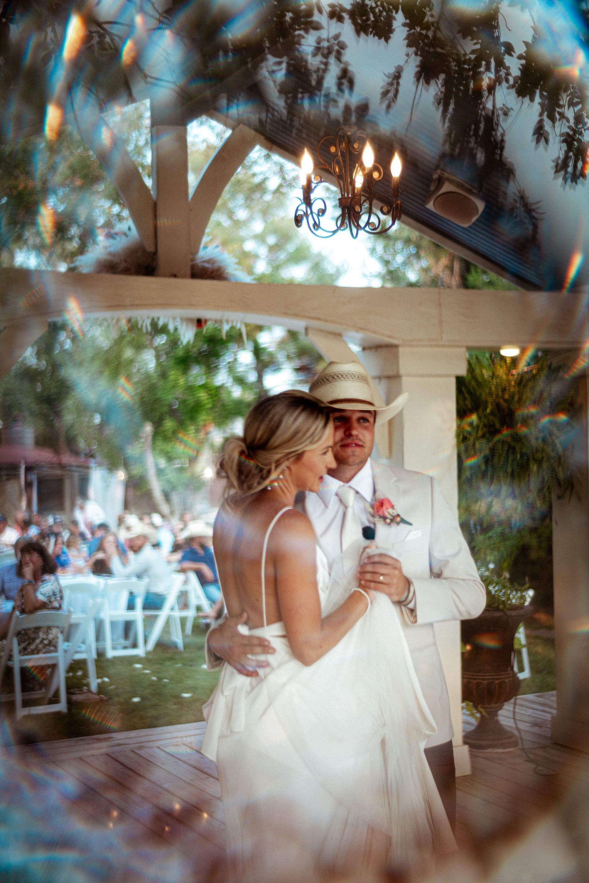 A bride and groom are dancing under a gazebo at their wedding reception.