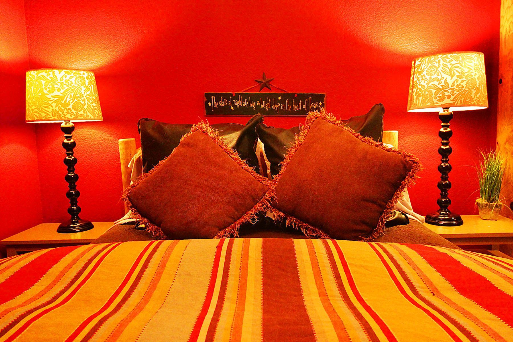 A bed with pillows and lamps in a room with a red wall