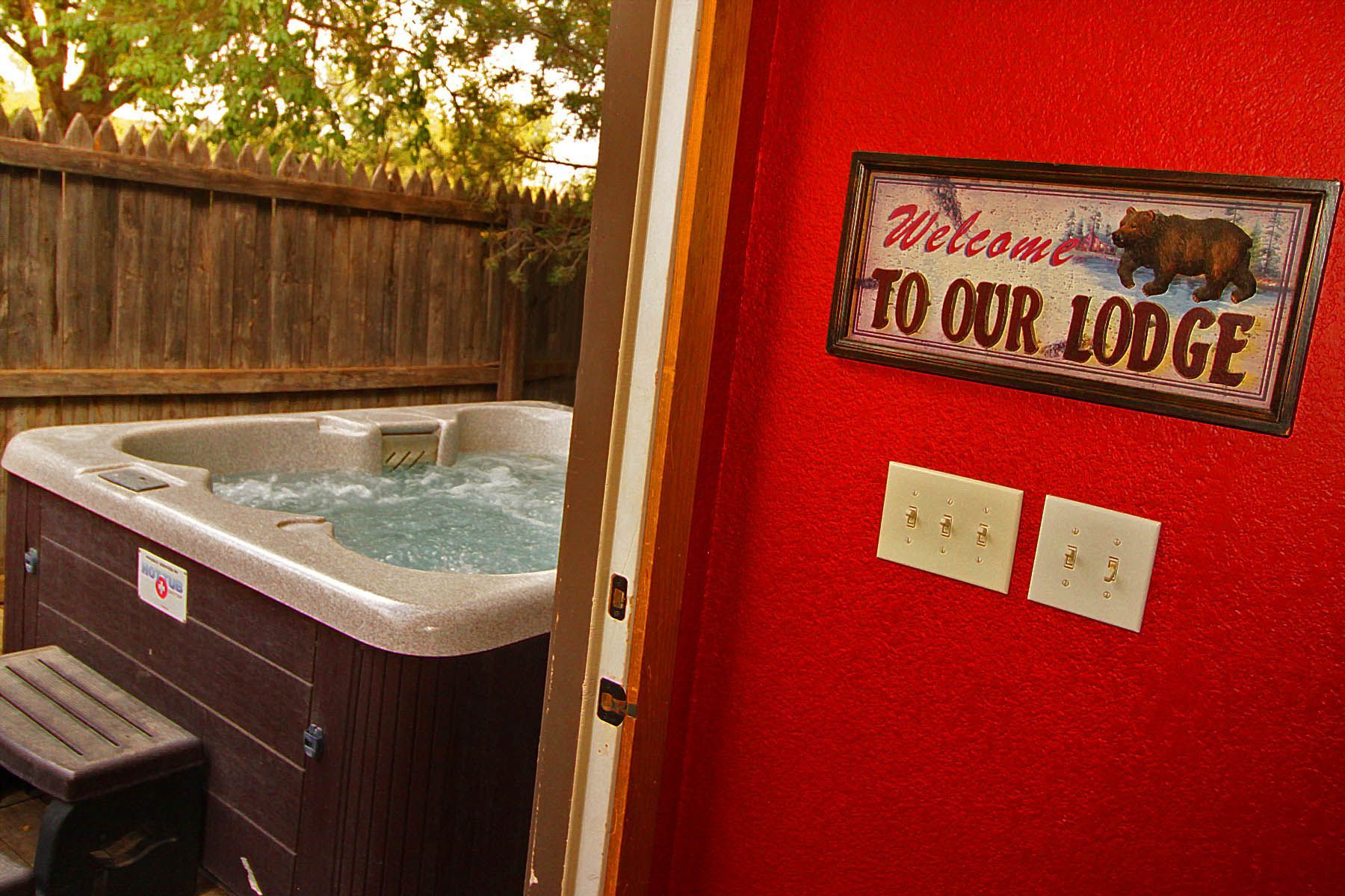 A hot tub with a welcome to our lodge sign above it