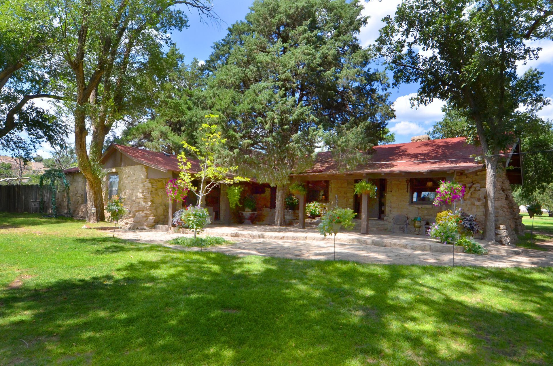 A large house with a red roof is surrounded by trees and grass.