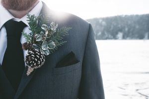 A man in a suit and tie with a pine cone on his lapel.