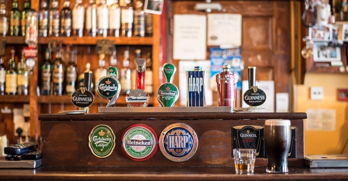 A bar with a lot of beer taps and bottles on the shelf.