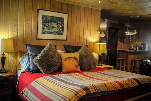 A bedroom with a bed , lamps , pillows and a picture on the wall.